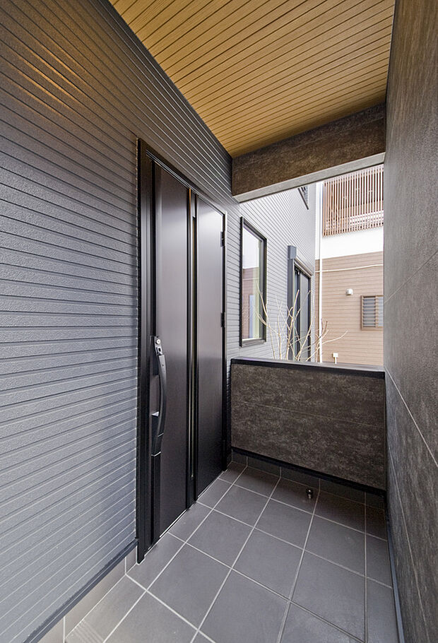 【2号地モデルハウス】玄関ポーチを覆うように壁で囲い、アクセントとなるよう質感の異なるサイディングを採用。