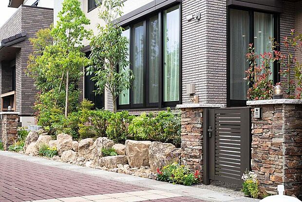 【外構デザイン】街の随所を彩る、久栗坂石や速玉石を大胆に用いたウォール。豊かな植栽と共に、森の中のような心地よさをもたらします。