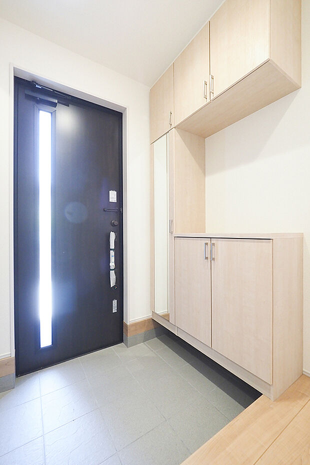 浮かせた下部収納と上部吊戸棚の充実したシューズ収納があり、清潔感のある動線が確保された玄関空間です。