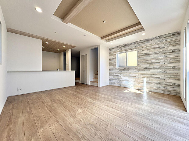 【7号棟/タタミコーナー含むLDK（20.5帖）】　キッチン上部は木目のポップアップ天井を施し、空間に奥行きをもたせました。その他、アクセントクロスや折上天井を採用し、表情豊かな住空間に仕上げています。