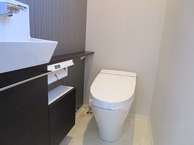 【タンクレストイレ】メーカー:リクシル タンクレス、便器はフチのないデザインでお掃除ラクラク!手洗い器上部にはトイレットペーパーやお掃除用具をきれいに収納でき、スッキリとした空間に。自動でフタが開き、使い勝手も抜群!