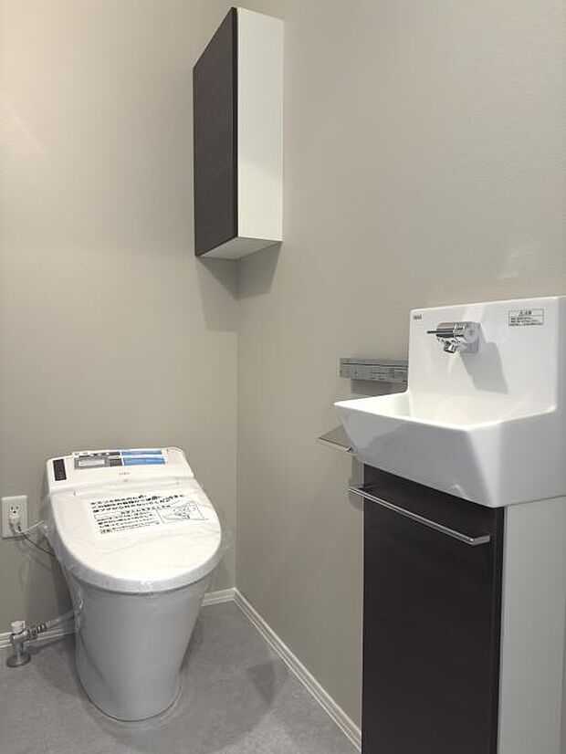 【No.3_1階トイレ(撮影_2024年6月)】1階はタンクレストイレを採用。トイレ内には手洗い器と収納が設置されています。