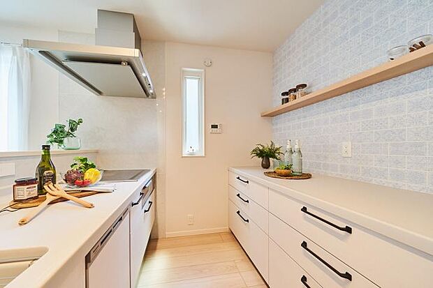 【No.1_キッチン（撮影_2023年7月）】ホワイトを基調とした清潔感のあるキッチンスペース。カウンター収納が標準設置済です。カウンター収納上部の壁紙も印象的な空間を演出しています。