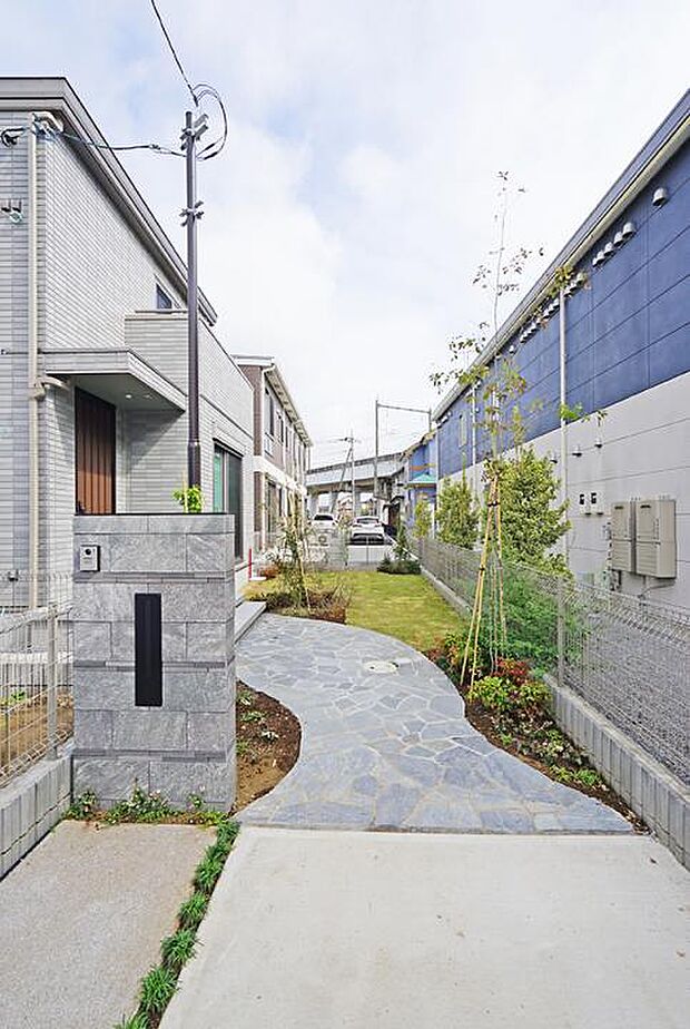 【No.7_外構（撮影_2025年10月）】玄関へ続くアプローチの奥には芝生のお庭スペースもあります。