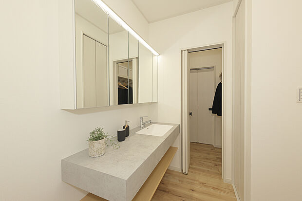 【モデルハウス写真(8号地)】
フロートタイプの洗面台がホテルライクな雰囲気。ご家族で並んで身支度ができるワイドサイズです。ファミリークローゼットに隣接しているので、洗濯物をそのまま掛けて収納可能。