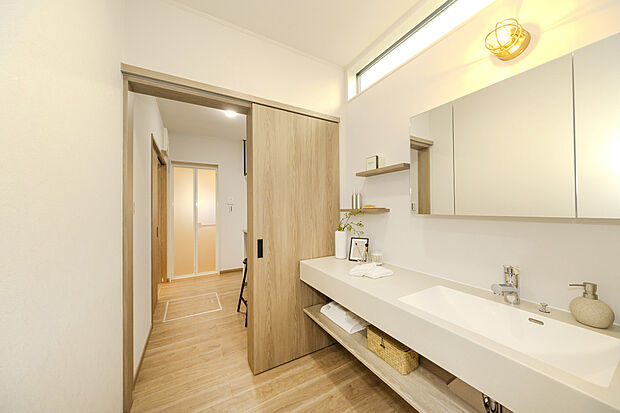 【洗面室/当社施工例】
ハイサイドライトから自然光が届く洗面室です。洗面台はホテルライクなデザインで、日常のちょっとした気分転換にも。カウンターは、メイクアップスペースとしてもゆったり使えるワイドサイ