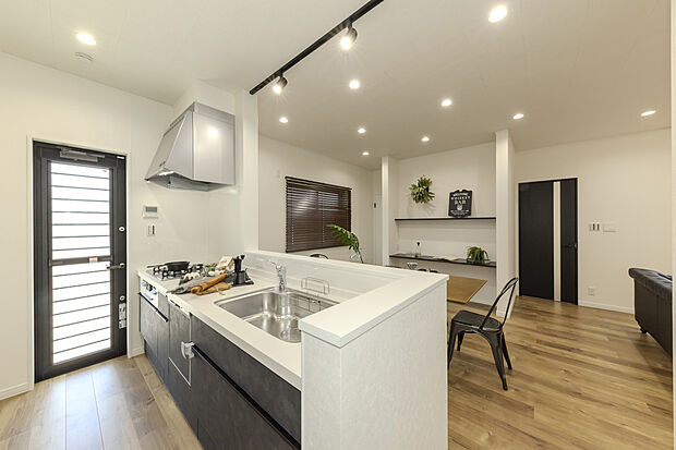 【【キッチン/当社施工例】】質感のあるキッチンパネルが高級感のある印象。開放感はそのままに、調理中の手元を隠せる腰壁を設け、生活感を抑えられるよう配慮しました。