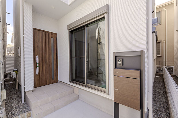 【【外観(2号地)】】玄関ドアはあたたかみのある木目調で外観のアクセントに。スリット入りのため、玄関内に自然光を導き、明るいエントランスが毎日の帰宅や来客を出迎えます。