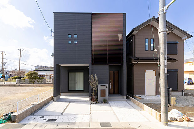 【【外観/当社施工例】】洗練された雰囲気を醸し出す、ダークカラー・スクエア型のスタイリッシュな外観です。バルコニーに設けられた木調のアルミルーバーが、全体のアクセントになっています。