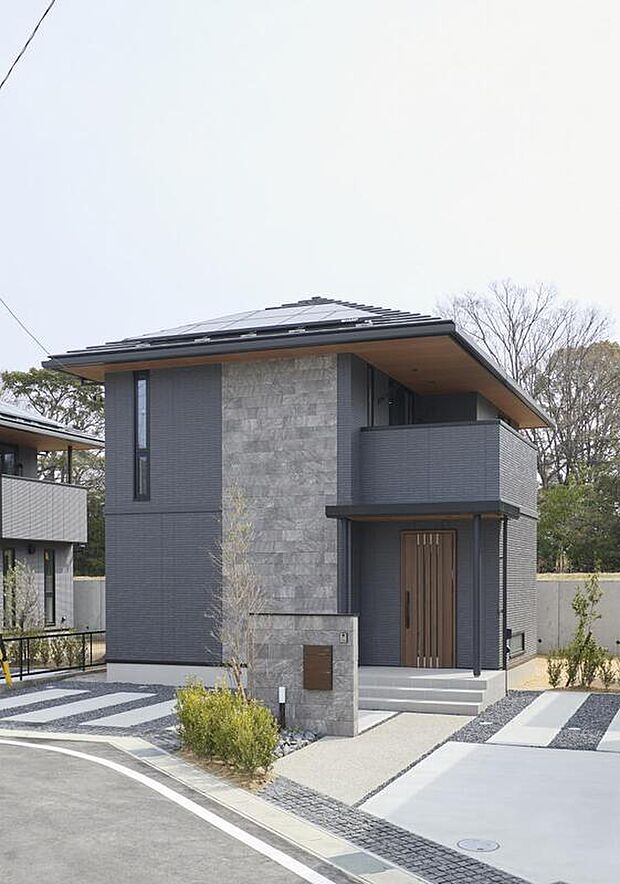 【現地外観写真】【J-7号棟外観】玄関ドアや軒の木目が温かみを添える邸宅。駐車スペースは4台分確保しており、ご夫婦揃って車を所有するだけでなく、急な来客の際にも慌てることなく対応可能です。