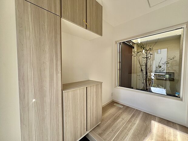 【【玄関/10号棟】】玄関をはいると窓から中庭を望むことができます。植栽を施しているので、四季の移ろいを感じることができそうです。※未入居住宅。