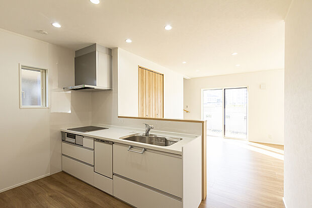 【1階キッチン/A号地モデルハウス】IHクッキングヒーターは立ち上がり部分が少なく、前面に壁を設けることでダイニングへの油跳ねを防ぎます。食器洗い乾燥機付きで、洗い物やお掃除の負担が軽減されます。