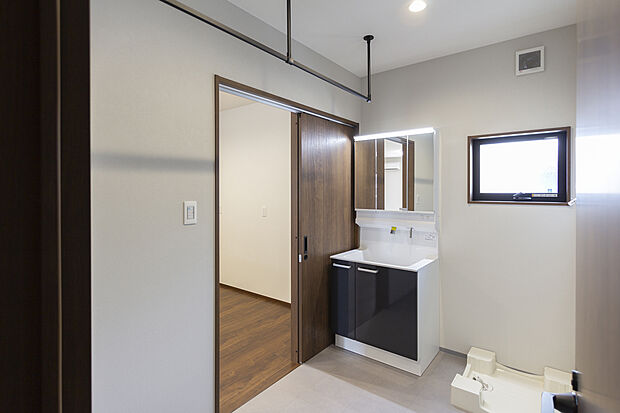 【【1階洗面所/D号地モデルハウス】】洗面室はゆとりある広さがあり、洗面化粧台は背後まで確認しやすい3面鏡タイプ。スタイリッシュな室内物干を備えました。洗濯物を洗う→干すが一か所で完結できて、機能的な水回りスペースです。