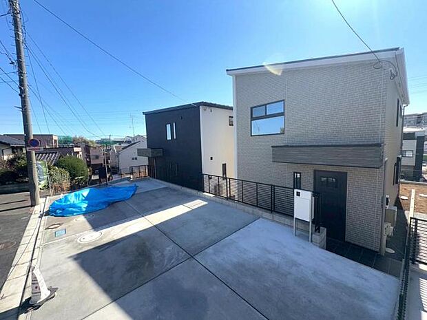 【【現地外観写真/左から1・2号棟】】車種により並列2台駐車が可能なカースペース。お車だけでなく、お子様の成長とともに増える自転車も一所にスッキリ。