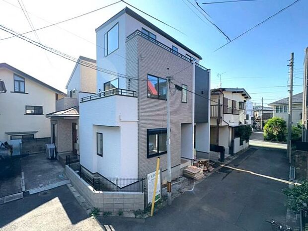 【【現地外観写真】】開放感溢れる南東角地!洗練されたモダンなデザインが目を引くスタイリッシュな新築3階建てです。便利なビルトイン車庫付きで快適な暮らしを実現。(2026年7月撮影)