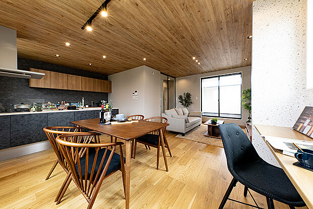 【【当社施工例/キッチン】】フラットキッチンを採用し、家族の顔を見ながら家事に集中できる間取り。ブラックを基調としたキッチンと木目調の天井が織りなすコントラストが、高級感を演出する一邸です。