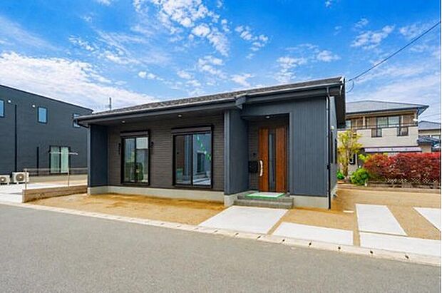 【1号地：重厚感と温もりが調和する平屋の外観】スタイリッシュなダークグレーの外壁に、木目調の玄関ドアが温かみをプラス。飽きのこない洗練されたデザインで、毎日の帰宅が楽しみになる佇まいです。