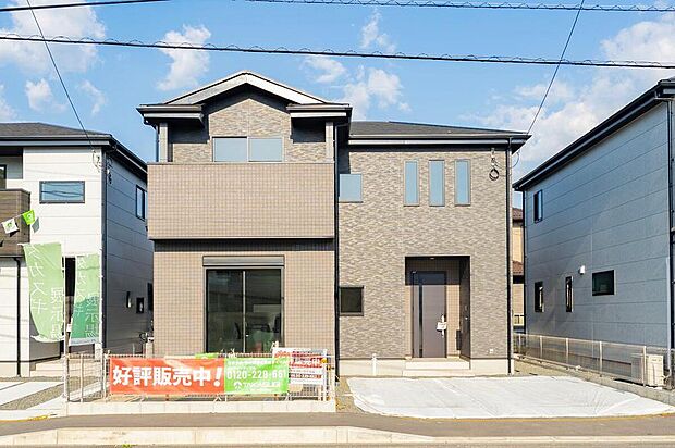 【現地外観写真(2号地)】【駐車2台＆18帖LDKの4LDK】 シックな外観の4LDK。並列2台駐車可で送迎も快適。18帖LDKや2帖のフリースペースなど、ゆとりの設計が魅力。家族の笑顔が広がる、温かい暮らしが始まります。