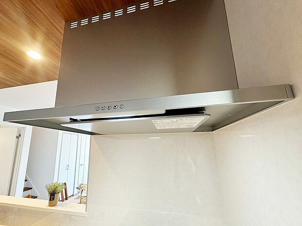 【レンジフード】背面の白い壁や、天井の木目調と非常によく調和しており、統一感のある美しいキッチン空間を作り出しています。