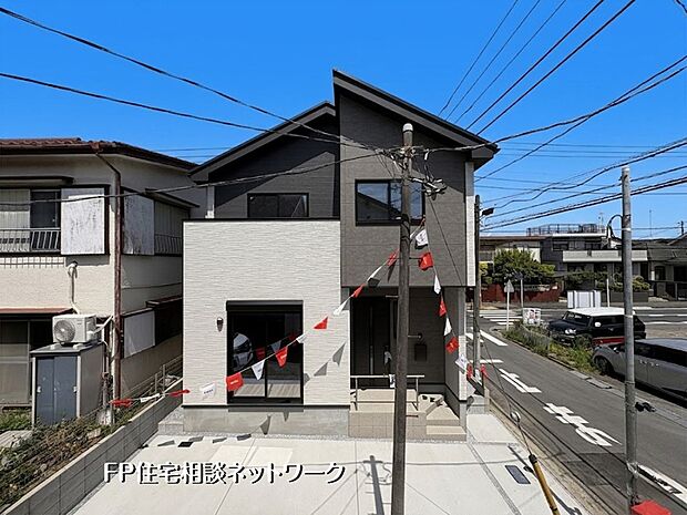 【現地外観写真】【外観】 モノトーンを基調としたスタイリッシュな外観が目を引く意匠性の高い住まい。青空に映えるシャープなシルエットと、落ち着いた色合いが調和しています。前面のスペースは開放感があり、毎日の暮らしを豊