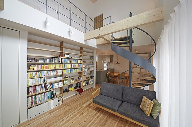 【M様邸】こだわりは吹き抜けリビングの中央に配置したらせん階段。キッチンダイニングとリビングの空間を分ける仕切りにもなっています。美しいオブジェのようでしょう。リビングにはオープンの本棚も取り付けているので、読書もはかどります。