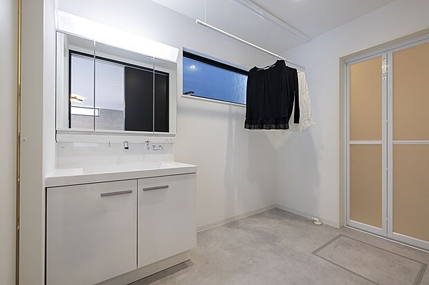 【【1階洗面所/1号地モデルハウス】】対面キッチン背面に水回りを集約することで、洗濯機のアラームなどに気づきやすく、家事の効率UP。ハイサイドライトから陽光が届く洗面所は、広さにゆとりがあり、昇降式の室内物干を備えています。