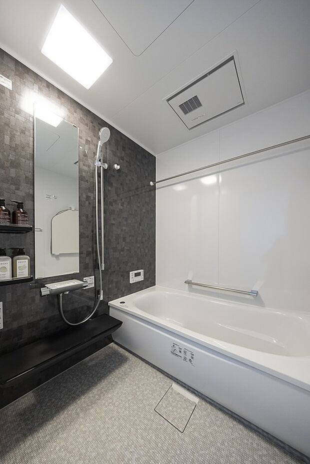 【【1階浴室/3号地モデルハウス】】光沢あるアクセントパネルが光を反射しつつ、落ち着いた印象のバスルーム。ゆったりとした浴槽を備えています。手すりやカウンター付きで使い勝手に配慮しています。