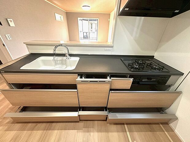 【6号棟 キッチン】キッチンテーブルはおしゃれなブラック、三ツ口ガスコンロとタッチレス水栓、食洗器もついているのでお料理上手なご家族にピッタリです!