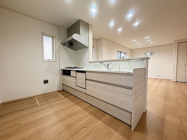 【《1号棟　キッチン》】対面式のキッチンです。リビングにいるご家族と会話をしながら、楽しくお料理ができます。手元を隠してくれる立ち上がりの壁があるので、丸見えにならない安心感もあります。