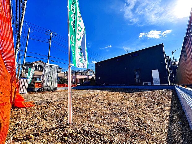 【【販売現地写真】外観2】2号棟西側が隣地エントランス&駐車場になっており、陽光を遮らず角地のような明るさと開放感がございます。