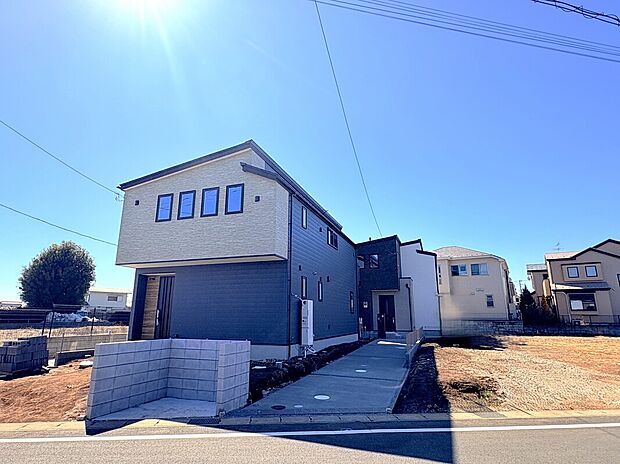 【現地外観】モダンなツートンカラーの外観が目を引く新築邸宅。カースペースや外構も整えられ、毎日の暮らしを軽やかに彩ります。落ち着いた住宅街で家族との穏やかな時間を育む新しいステージに最適の一棟です。