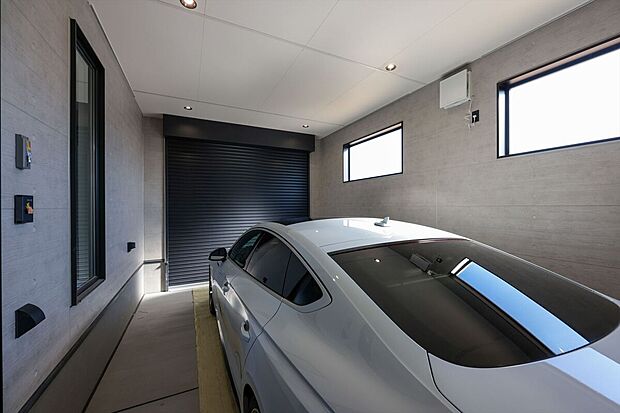 【１号棟ガレージ】大切に守り、美しく魅せるビルトインガレージ 。室内やホールから直接出入りできる便利な動線を確保しました 。照明付きの洗練された空間で、天候を気にせず趣味の時間を心ゆくまで楽しめます。