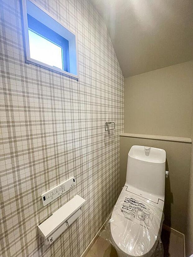 【【トイレ/1階】】毎日使用するトイレは、チェック柄のクロスで可愛らしい雰囲気に。寒い季節も快適に使用できる温水洗浄便座付きです。背部に棚があり、芳香剤やインテリア雑貨を飾ることができます。