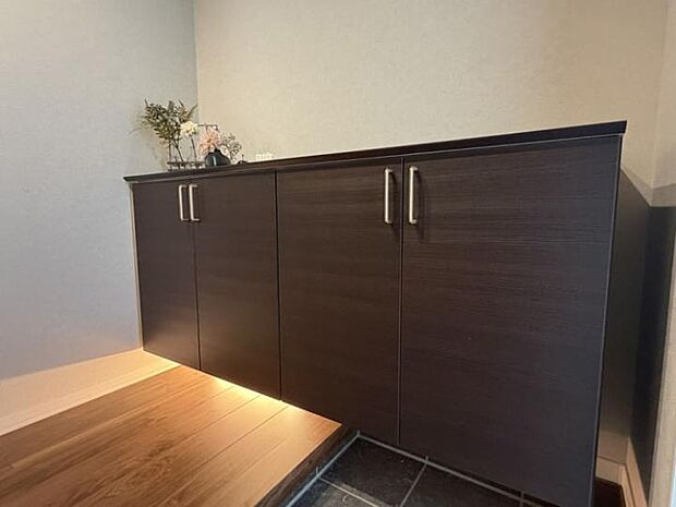 【玄関】カウンターに季節の演出と間接照明でお客様をお出迎えでき、コート掛けも隣接していつでもスッキリ空間(2025年11月撮影)