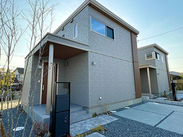 【5号地外観】
タイル外壁と木目調の軒天が調和した落ち着きある玄関まわり。インターホン・ポスト・宅配ボックス一体の門柱で、すっきりとした印象に。統一感ある街並みに美しくなじむ外構です。