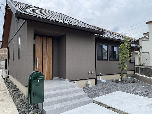 落ち着いたトーンの外壁に、木目のドアが映える自慢の玄関。グリーンのポストが毎日の帰宅を楽しくしてくれます。