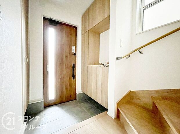 【玄関】落ち着いた木目のドアとシックな外観が調和した玄関。雨の日でも安心なカーポートと段差の少ないアプローチで、毎日の出入りが快適です。玄関横のスペースは自転車やベビーカーなどの一時置きにも便利です。