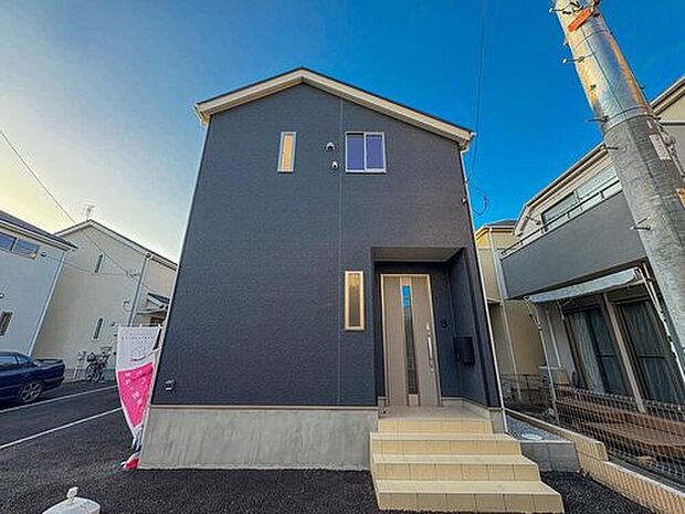 【現地外観写真】青空に映えるダークカラーの外観が印象的な新築戸建て。家族の笑顔が輝く、快適で洗練された毎日をここから始めませんか。