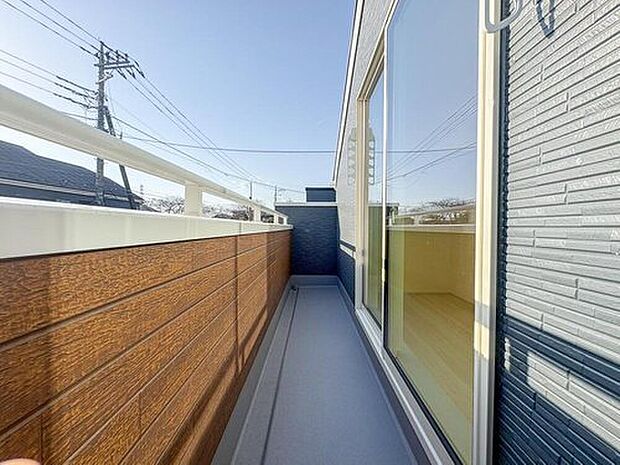 【バルコニー】明るい陽光と心地よい風を招き入れるバルコニー。木目調の壁が温かみを添え、家族の日常に開放感をもたらします。