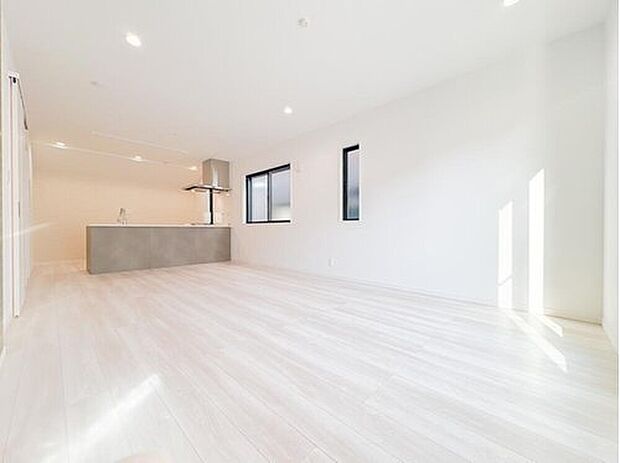 【リビング】柔らかな陽光が注ぎ込む、開放感あふれるワイドリビング。白を基調とした空間にグレーのキッチンが洗練されたアクセントを加えます。ダウンライトがスッキリとした天井を演出し、広々とした寛ぎの時間を叶えます。