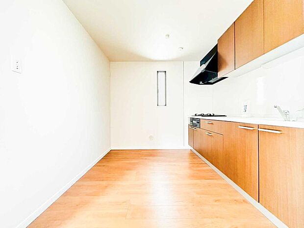 【キッチン】奥までしっかり広がるキッチンスペースで、ゆとりある動線を実現。木目キャビネットが映えるスッキリとした壁付けキッチンは、収納も作業もしやすい快適仕様です。