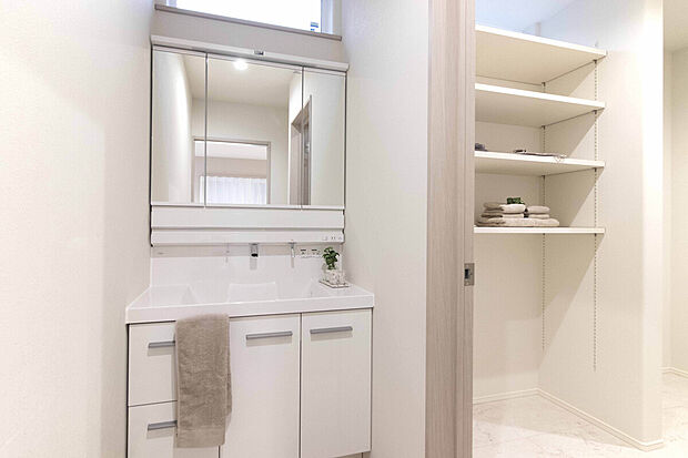 【No.1号棟 洗面所】洗面台横に収納スペースを備え、タオルや日用品もすっきり整理。朝の身支度やお風呂あがりの時間も快適に使えます。