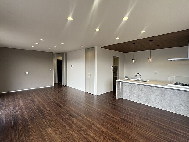 【W-25】キッチン・リビング。
キッチンの奥にあるドアは、パントリー＆ランドリールームのクローゼット。２つの大型収納を1階に設けたプランです。※一部内装工事中です。26年1月30日撮影