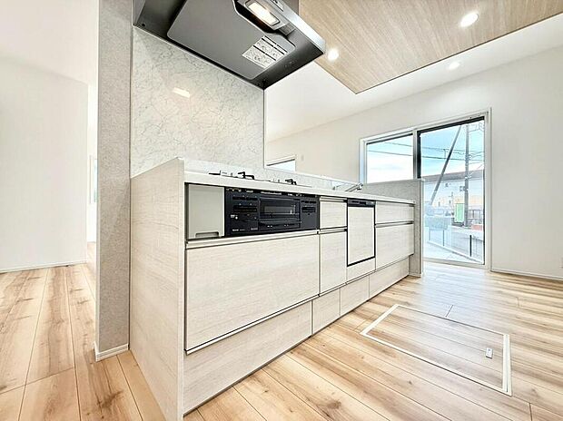 リビングが見渡せる開放的なアイランドキッチン。食洗機や3口コンロ、床下収納を標準装備し、機能性とデザイン性を両立させました。ナチュラルな木目調の内装が、LDK全体の温かい雰囲気と調和しています。