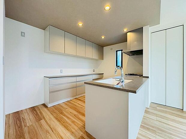 【◇◆キッチン＆カップボード◆◇】LDKのインテリアに溶け込む、美しいデザインのキッチン。折下天井に設置された照明の明かりが、より魅力的に演出します。フルフラットキッチンを採用し、自然とご家族のコミュニケーションを育みます。