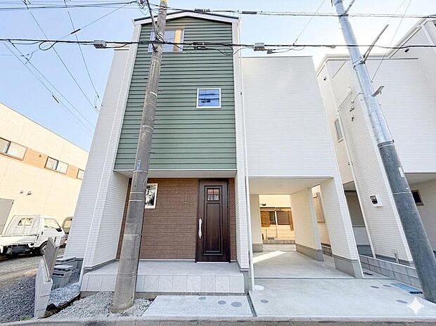 【現地外観写真】ホワイトを基調にグリーンとブラウンを組み合わせた、印象的な2トーン外観。縦のラインを強調したシャープなデザインが、すっきりとした都会的な佇まいを演出します。