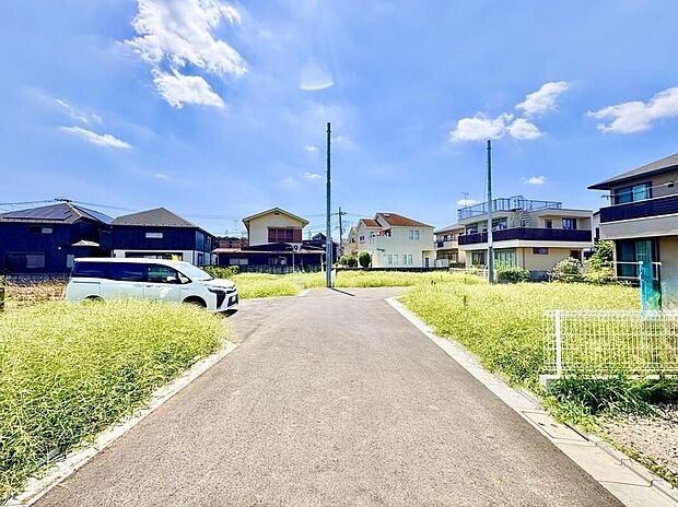 【現地外観写真】青空が広がる穏やかな住宅街。この道は、家族の笑顔と新しい思い出を育む場所へと繋がります。