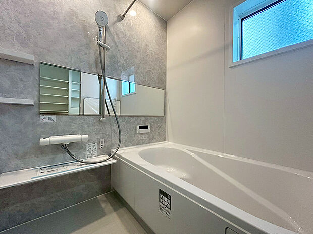 【浴室　D号棟現地写真】■リクシル　システムバスルーム「AX」。フロアはスポンジが奥まで入り掃除がラクラク。また独自の断熱層を使用しているため冬場でも冷やっとしません。