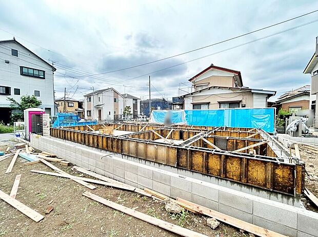 【現地外観写真】基礎の型枠が組まれた建築現場の外観写真です。周囲は住宅街で仮設トイレや資材が確認できます。現地(2026年9月)撮影。