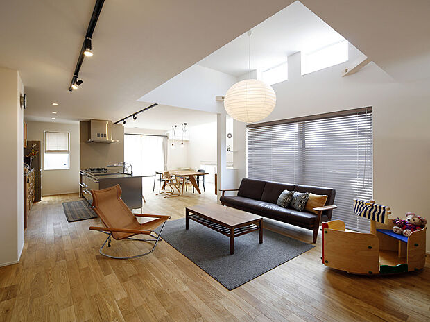 【弊社施工実例】リビングのハーフ吹き抜けから降り注ぐ陽射しは、LDK全体を明るく照らすための大事な役割を担っている。無垢のフローリングや木製家具が良く調和している。